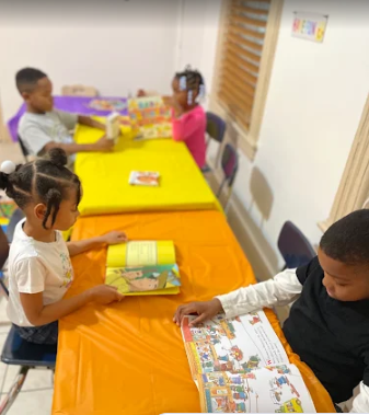 Children reading picture books together at the Happy Little Hearts tables